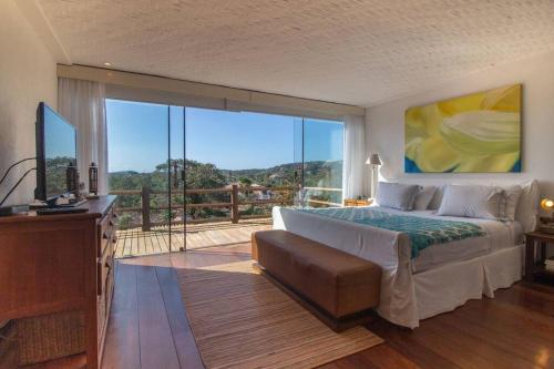 a bedroom with a large bed and a balcony at Mansão Imponente com Seis Suítes a 1min das Areias Praia da Ferradura Por Luxury Rentals in Búzios