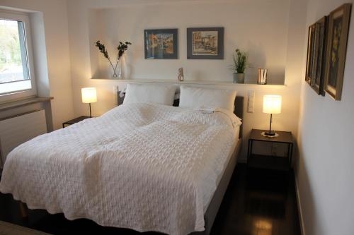 a bedroom with a white bed with two lamps at Schatzlhof Suite in Berg am Starnberger See in Berg am Starnberger See