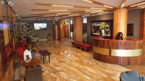 een lobby met een bar en mensen aan tafel bij Murex Plaza Hotel & Suites in Monrovia