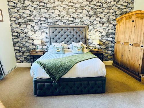 a bedroom with a large bed with a stone wall at Old Orchard Cottage, Wykeham in Scarborough