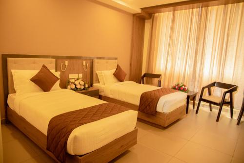 una habitación de hotel con 2 camas y una silla en Hotel Harisree Kollam, en Kollam