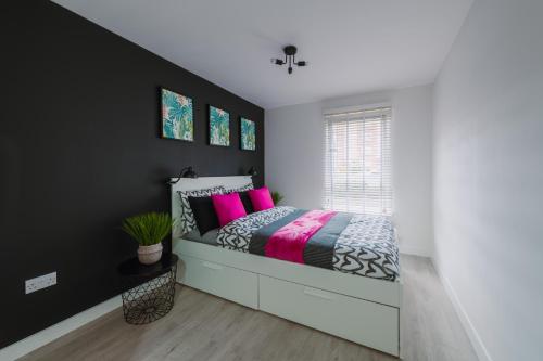 a bedroom with a bed with pink pillows at ComfySleep Apartments in Glasgow