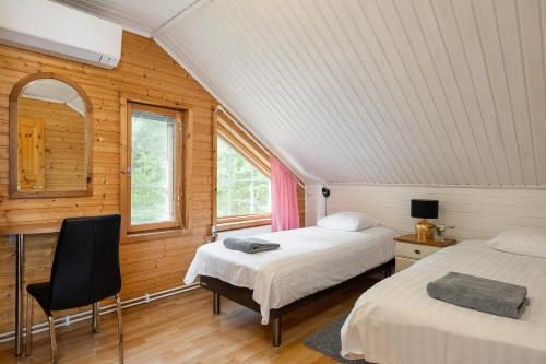 2 Betten in einem Zimmer mit Holzwänden und Fenstern in der Unterkunft Lehmonkärki Resort in Asikkala