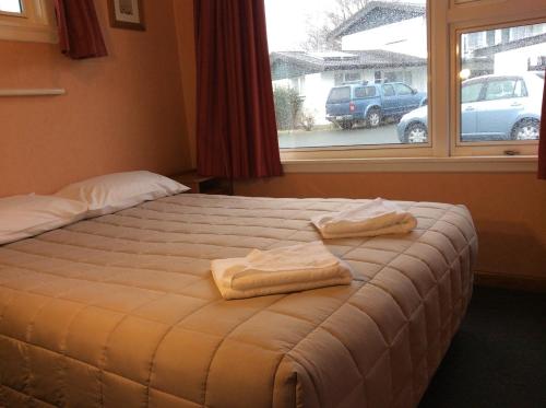 a bed with two towels on it in a room with a window at Belle Bonne Motel in Christchurch