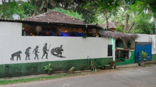 a building with a mural of surfers on the wall at Hostel Tharu, Surf Camp & Restaurant in Unawatuna