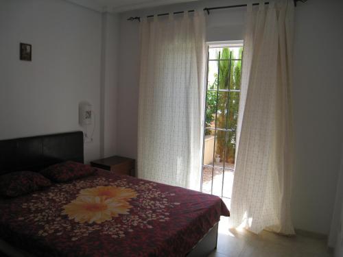 トレビエハにあるBungalow Altos de la Bahiaのベッドルーム1室(ベッド1台付)、窓(カーテン付)