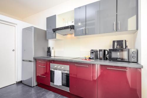 a kitchen with red cabinets and stainless steel appliances at Le 10-GregIMMO-Appart'Hôtel in Belfort