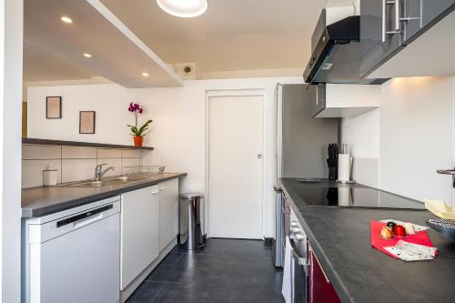 a kitchen with white cabinets and a black counter top at Le 10-GregIMMO-Appart'Hôtel in Belfort