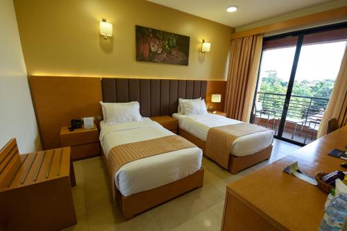 a hotel room with two beds and a balcony at K Hotels Entebbe in Entebbe