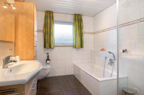 Un baño con lavabo, bañera e inodoro. en Haus Blaulichtfamilie, en Opfenbach
