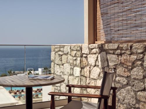 a table and chairs in a room with a stone wall at The Royal Senses Resort & Spa Crete, Curio Collection by Hilton in Panormos Rethymno
