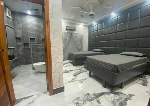 a bedroom with two beds and a bathroom with a tub at The Bahria Town Hotel & Suites in Lahore