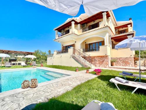 a villa with a swimming pool in front of a house at Luxury Villa Makris with private heatable pool in Kavvadádes