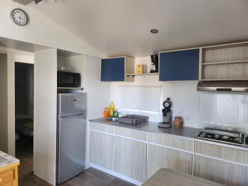 a kitchen with stainless steel appliances and blue cabinets at Mobil-home cosy 166 in Narbonne