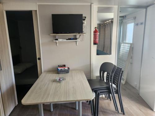 Mobil-home cosy 166 في ناربون: غرفة صغيرة مع طاولة وكراسي وتلفزيون