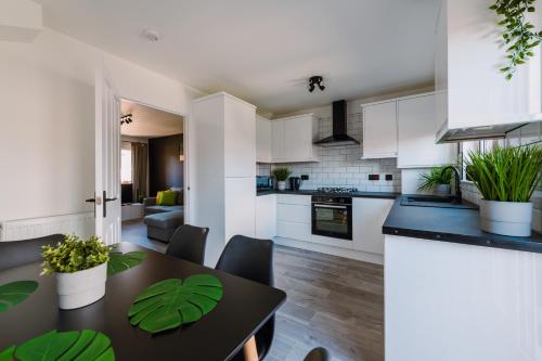 a kitchen and living room with a table and chairs at Emirates ApartHOUSE in Glasgow