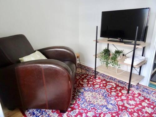 a living room with a leather chair and a television at Studio in the center area with free street parking in Vaasa