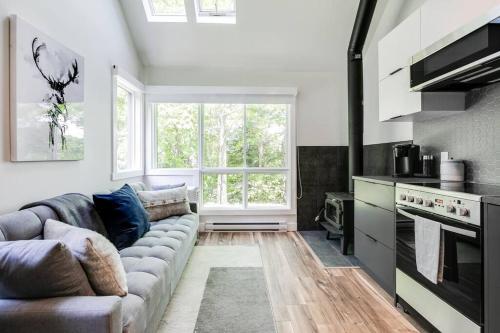 a living room with a couch and a large window at Le Petit Condo B - Ski In/ Ski Out Mont-Tremblant in Mont-Tremblant