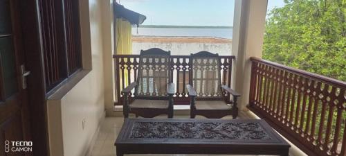 a balcony with two chairs and a view of the ocean at New Mahrus Hotel Lamu in Lamu