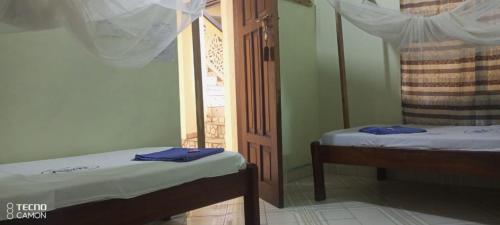 a room with two beds and a door with a window at New Mahrus Hotel Lamu in Lamu