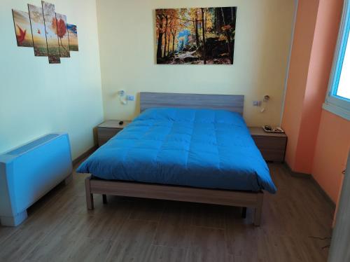 Un dormitorio con una cama azul y una pintura en la pared en Villa ARA blu, en Canegrate