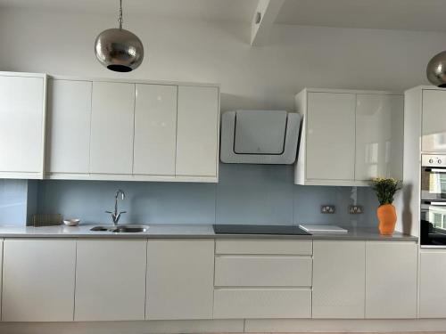 a white kitchen with white cabinets and a sink at Elegant 1st Floor 1BR Belsize Park Apartment in London