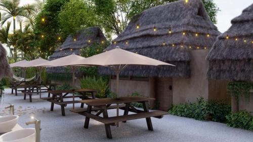 a row of tables and umbrellas in a courtyard at Maya Cabaña Hostel in Bacalar