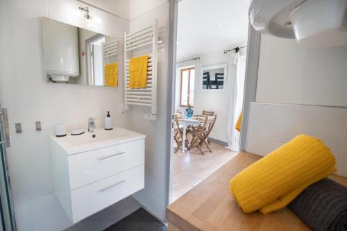 een kleine badkamer met een wastafel en een gele stoel bij L'Isle en Blanc - Appartement hypercentre - 4 couchages in LʼIsle-sur-la-Sorgue