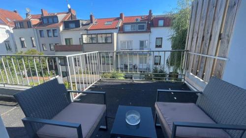 d'un balcon avec deux chaises et une table et certains bâtiments dans l'établissement Air Apartments 5, à Brême