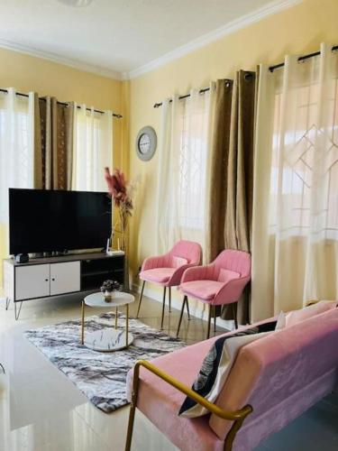 een woonkamer met roze stoelen en een flatscreen-tv bij Clementine’s Subdivision House in Oroquieta