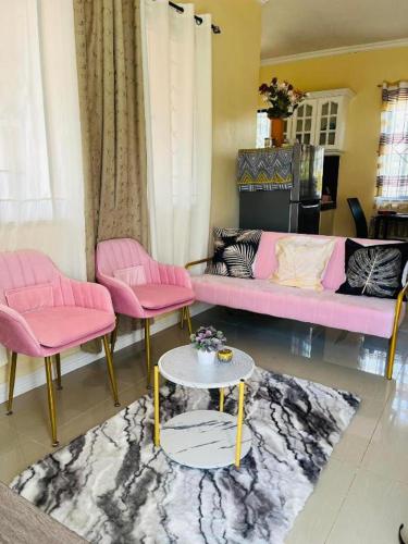 een woonkamer met een roze bank en roze stoelen bij Clementine’s Subdivision House in Oroquieta