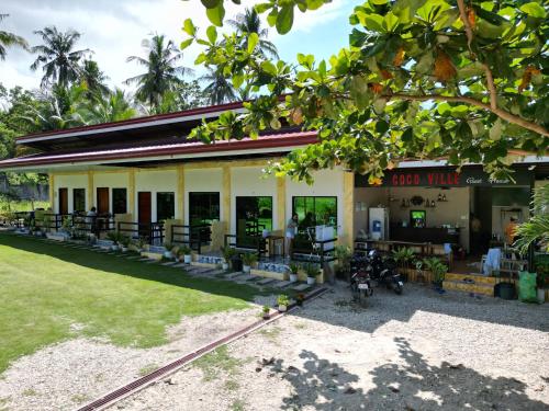 een gebouw met tafels en stoelen ervoor bij CocoVille Guesthouse in Alegria