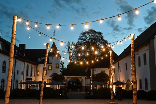 a string of lights over a courtyard with umbrellas at Chateau d'Urspelt in Urspelt