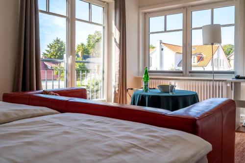 ein Schlafzimmer mit einem Sofa, einem Tisch und Fenstern in der Unterkunft Hotel Gregory Wyk auf Föhr in Wyk auf Föhr