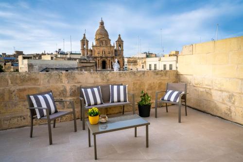 Siġġiewi的住宿－The Siggiewi Suites，美景阳台配有三把椅子和一张桌子
