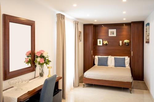 a bedroom with a bed and a desk with a vase of flowers at The Siggiewi Suites in Siġġiewi