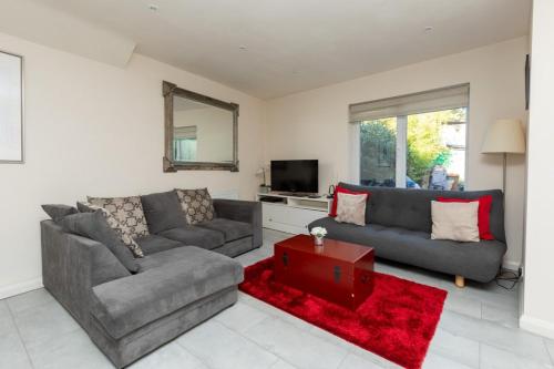 a living room with a gray couch and a red rug at Bright & Contemporary 1bedroom Annexe - Herne Hill! in London