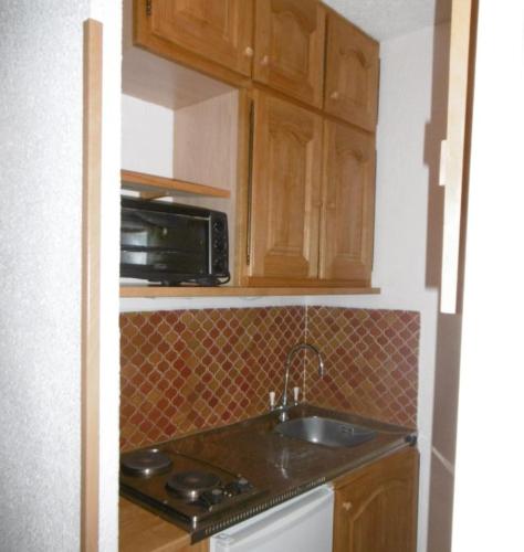 une petite cuisine avec un évier et un micro-ondes dans l'établissement Studio 4 couchages Risoul cœur de la station, à Risoul