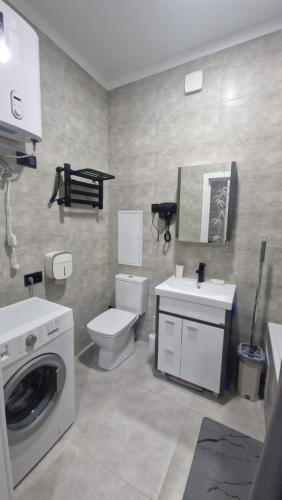 een badkamer met een wasmachine en een toilet bij Апартаменты в ЖК Мерей in Karagandy