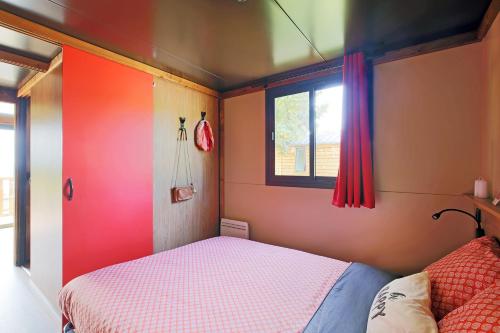 Huttopia Fontvieille في فونتفيل: غرفة نوم صغيرة بها سرير ونافذة