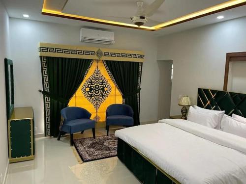 a bedroom with a bed and two blue chairs at Dream Inn Guest House in Islamabad