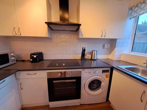 a kitchen with a sink and a washing machine at Exquisite Holiday Home 3 minutes from Dartford Station in Kent