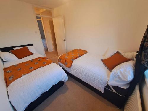 Exquisite Holiday Home 3 minutes from Dartford Station في Kent: غرفة نوم بسريرين وباب لغرفة اخرى