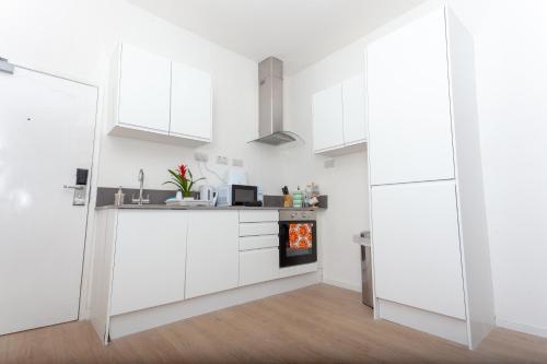 a kitchen with white cabinets and a stove at One Bedroom Serviced apartments Flat 311 in Birmingham