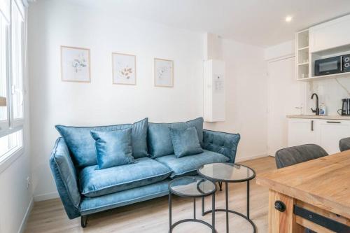 un salon avec un canapé bleu et deux tables dans l'établissement F2 hypercentre - Proche gare - WIFI gratuite, au Havre