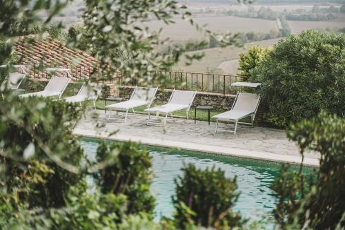 una fila di sedie bianche sedute accanto alla piscina di Montestigliano a Sovicille
