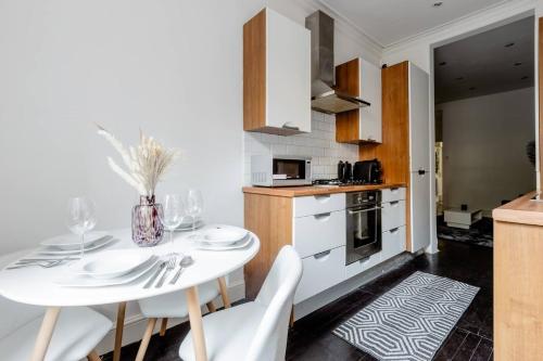a kitchen with a white table and white chairs at Spacious Apt In Central London in London