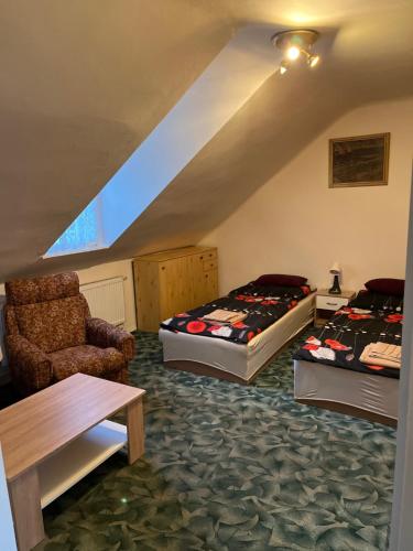 Cette chambre mansardée comprend deux lits et une chaise. dans l'établissement Štítová kolonie, à Ostrava