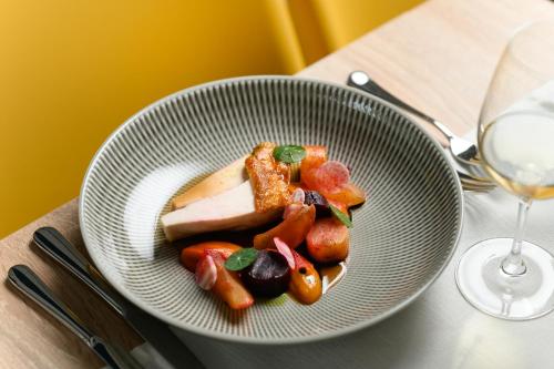 a plate of food on a table with a glass of wine at Mövenpick Balaland Resort Lake Balaton in Szántód
