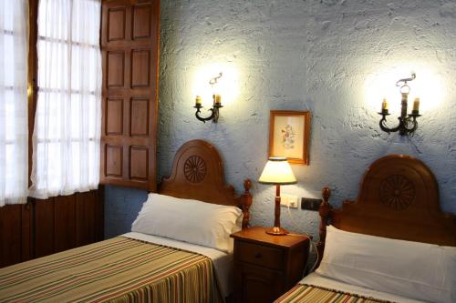 1 dormitorio con 2 camas y pared azul en Hotel Hermanos Macias, en Ronda